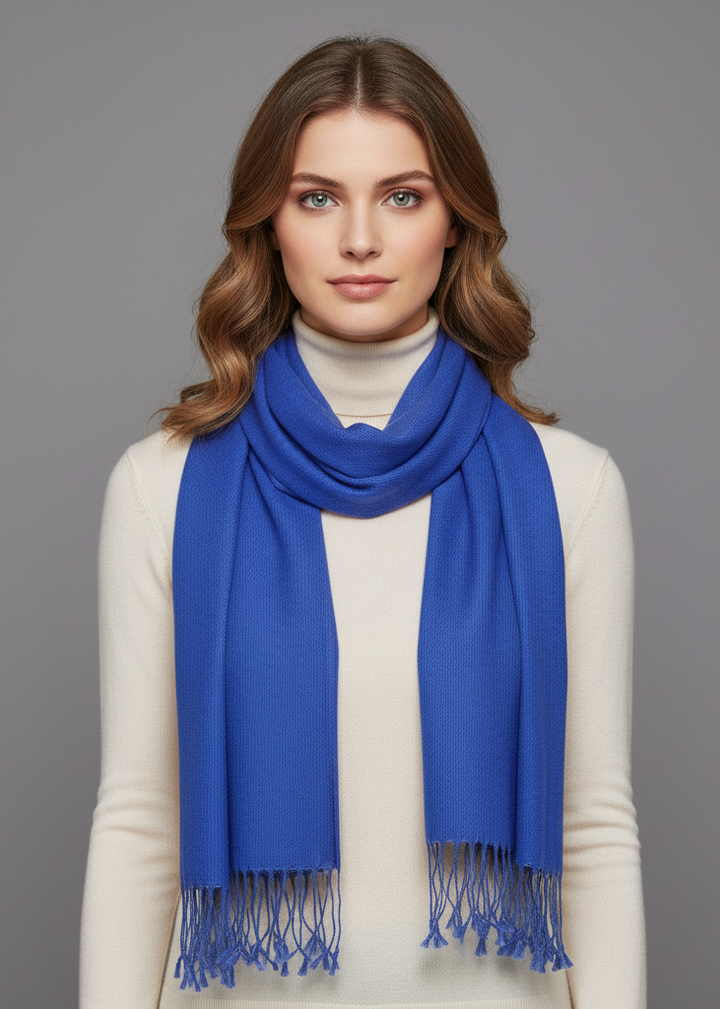 Blue cashmere and silk scarf elegantly draped over the shoulders of a person wearing a formal dress, showcasing the soft texture and luxurious drape of the fabric.