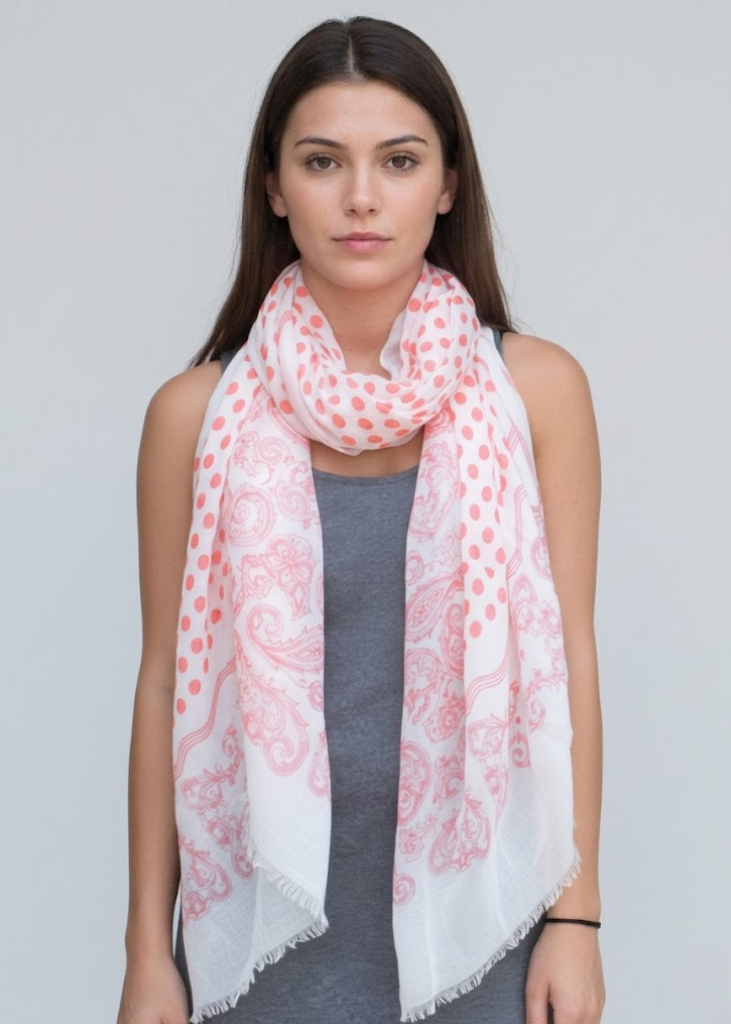 Lightweight coral gauze pashmina scarf with a decorative paisley border, polka dot center, and soft eyelash fringe.