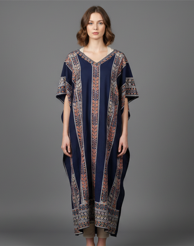 Woman modeling a full-length navy blue maxi kaftan dress featuring vertical floral stripe patterns in terracotta and cream. The one-size gown has a V-neckline and draped sleeves, shown in a professional studio shot against a solid grey background.
