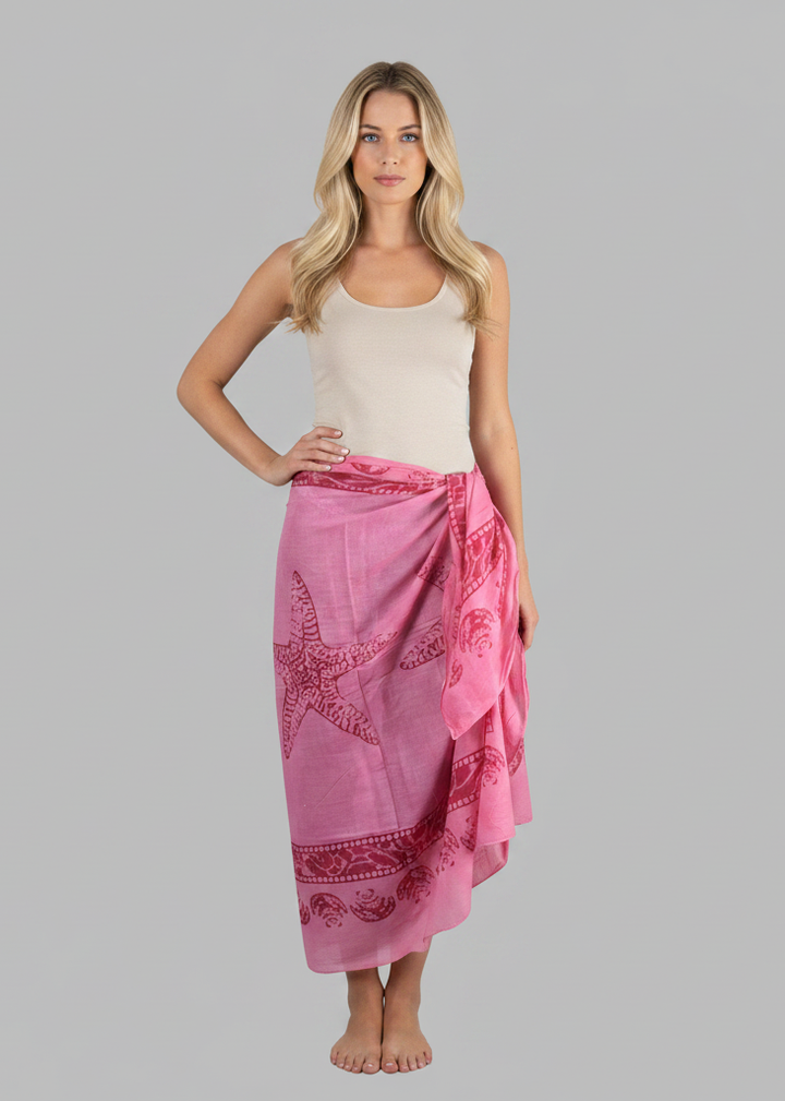 Pink women's Hawaiian sarong beach wrap cover up featuring a white floral tropical print and fringed edges.